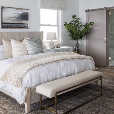 Modern bedroom with a bed, bench, and decorative elements.
